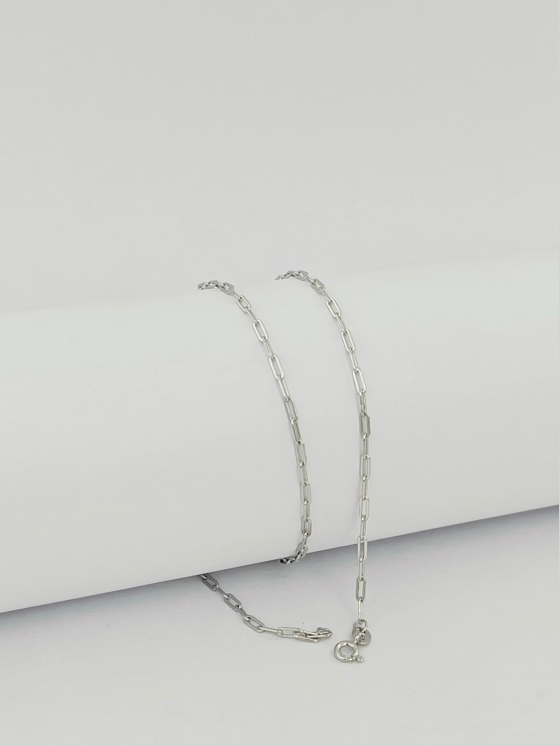 Silver chain necklace on a light gray background